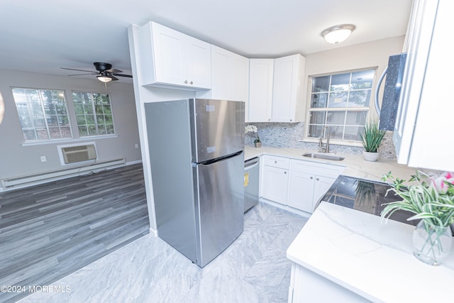 kitchen with tasteful backsplash, sink, white cabinets, appliances with stainless steel finishes, and a baseboard heating unit