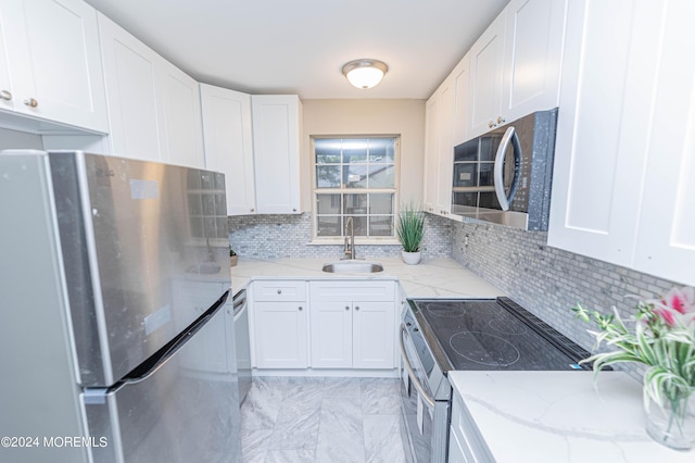 kitchen with white cabinets, stainless steel appliances, decorative backsplash, and a sink