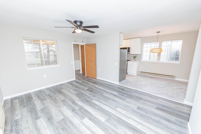 unfurnished living room featuring baseboard heating, baseboards, ceiling fan, and light wood finished floors