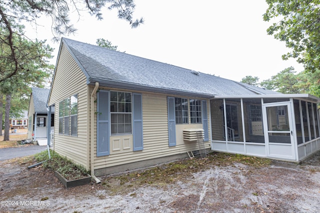 exterior space with a shingled roof and a sunroom
