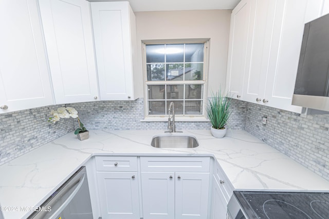 kitchen with light stone counters, white cabinets, backsplash, and sink