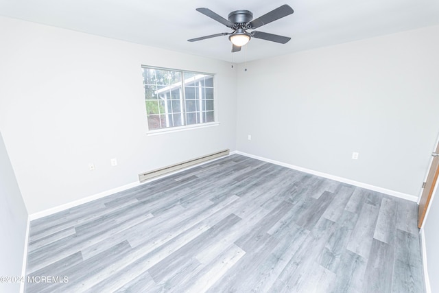 spare room featuring wood finished floors, a ceiling fan, a baseboard heating unit, and baseboards