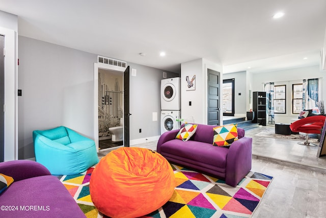 living room featuring stacked washer and clothes dryer and light hardwood / wood-style flooring