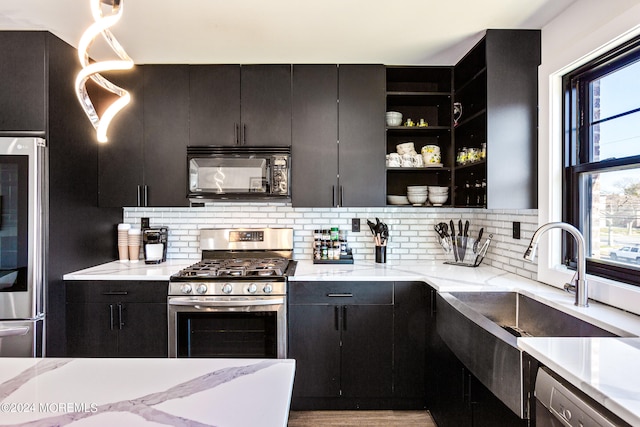 kitchen featuring light stone counters, stainless steel appliances, tasteful backsplash, sink, and light hardwood / wood-style flooring