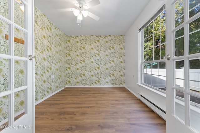 spare room featuring ceiling fan, a baseboard heating unit, and dark hardwood / wood-style floors