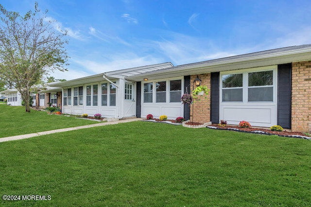 ranch-style home with a front yard, a garage, and a sunroom