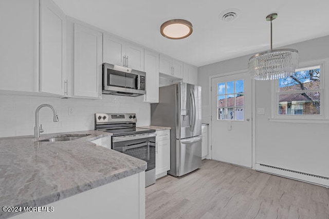 kitchen with appliances with stainless steel finishes, white cabinets, decorative light fixtures, sink, and a baseboard heating unit