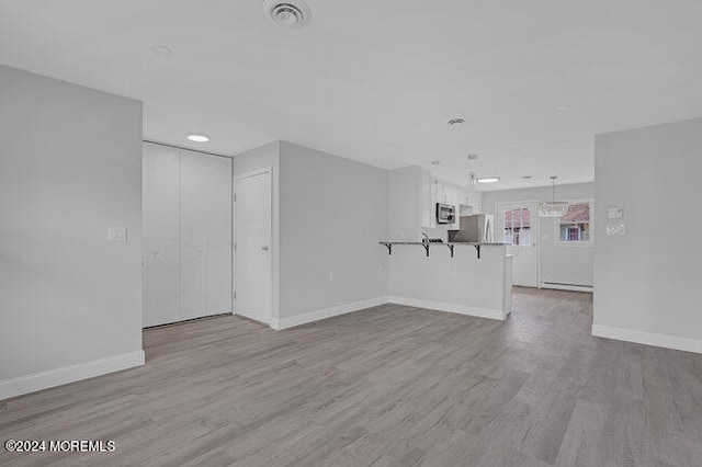 unfurnished living room with light wood-type flooring and baseboard heating