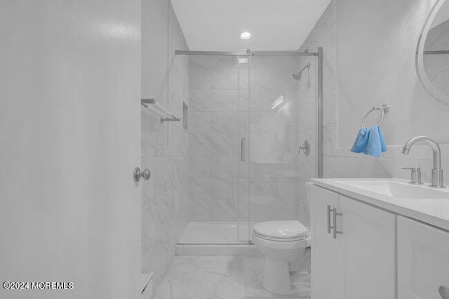 bathroom with tile walls, vanity, toilet, and an enclosed shower