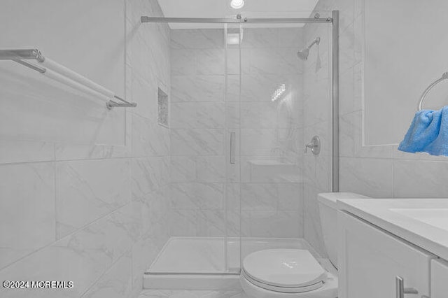 bathroom featuring vanity, tile walls, toilet, and an enclosed shower