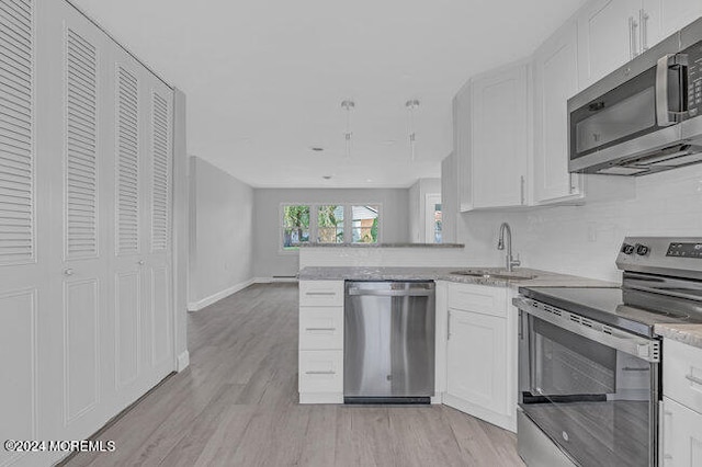 kitchen featuring sink, white cabinets, kitchen peninsula, light hardwood / wood-style flooring, and stainless steel appliances