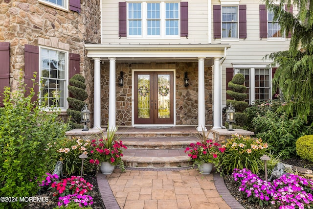 view of exterior entry featuring french doors and covered porch