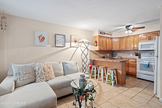 tiled living room with a textured ceiling, ceiling fan, and sink