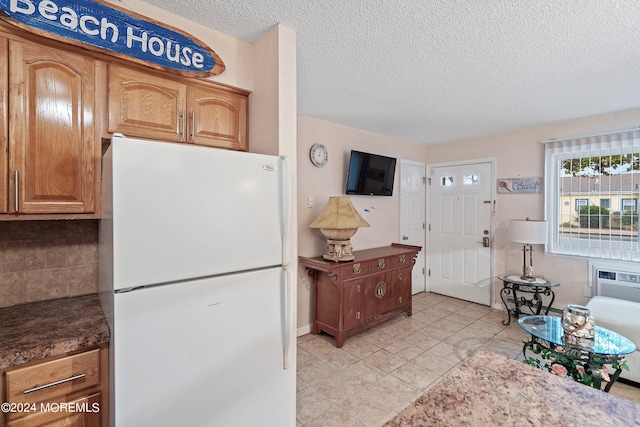 kitchen with a textured ceiling, light tile patterned flooring, white fridge, and tasteful backsplash