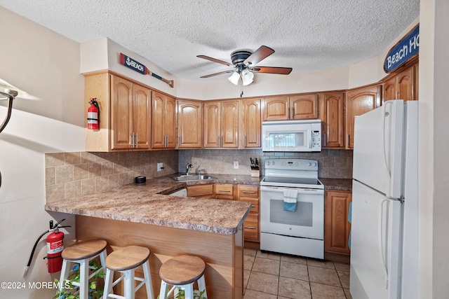 kitchen featuring a breakfast bar, white appliances, kitchen peninsula, ceiling fan, and sink