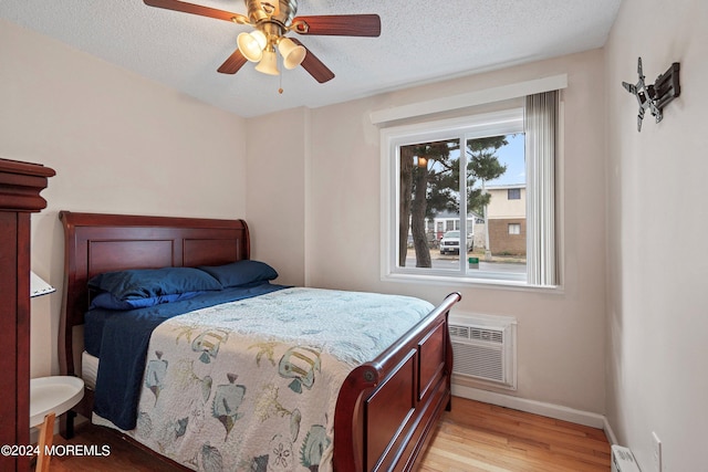 bedroom featuring ceiling fan, a textured ceiling, light hardwood / wood-style flooring, and a baseboard radiator