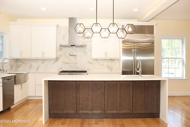 kitchen with hanging light fixtures, a kitchen island, island exhaust hood, appliances with stainless steel finishes, and light hardwood / wood-style floors