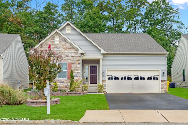 view of front of home with cooling unit, a garage, and a front yard