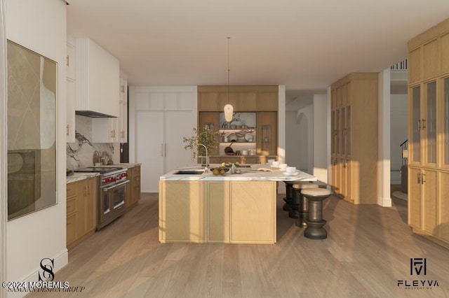 kitchen with hanging light fixtures, backsplash, light wood-type flooring, high end range, and sink