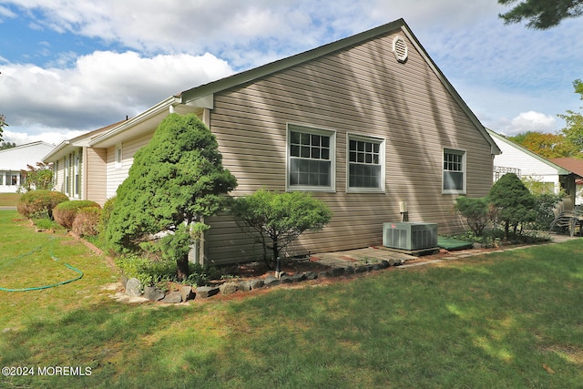 view of side of home with a yard and central AC