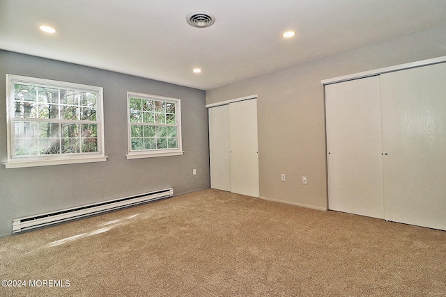 unfurnished bedroom with multiple closets, a baseboard radiator, and carpet