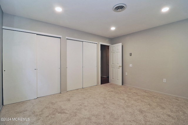 unfurnished bedroom with light carpet and multiple closets