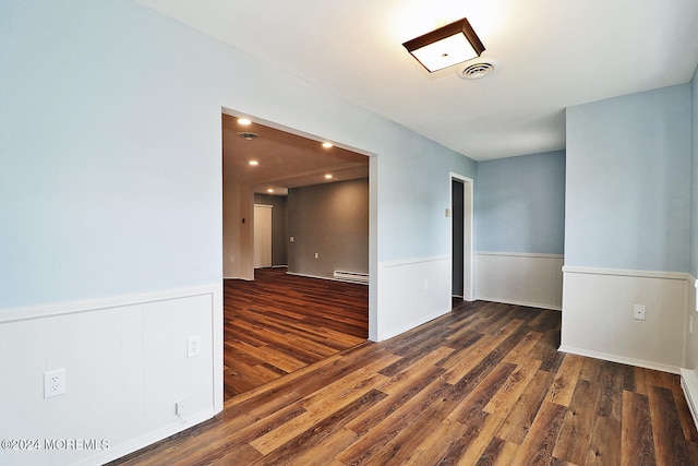 unfurnished room featuring baseboard heating and dark hardwood / wood-style floors