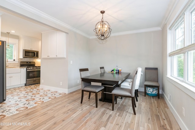 dining area with light hardwood / wood-style floors, ornamental molding, and a chandelier