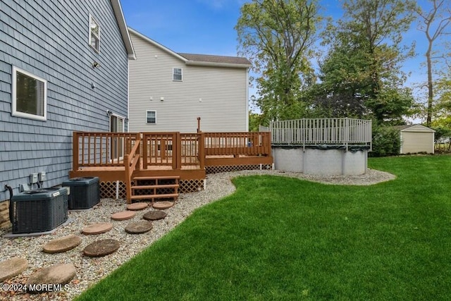 rear view of property with a wooden deck, central AC unit, and a lawn