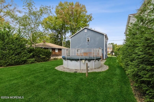 rear view of property featuring a covered pool and a yard