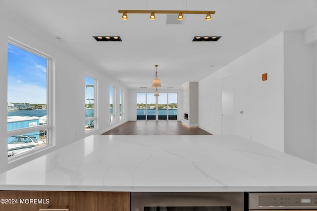 kitchen featuring pendant lighting, light stone counters, and beverage cooler