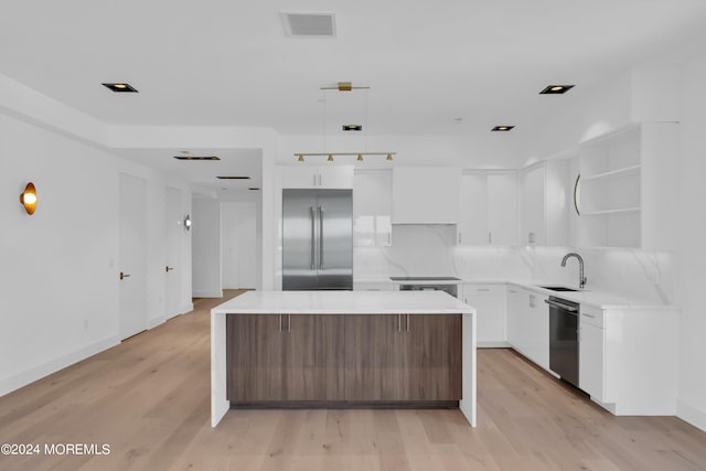 kitchen featuring white cabinets, sink, light hardwood / wood-style flooring, a kitchen island, and stainless steel appliances