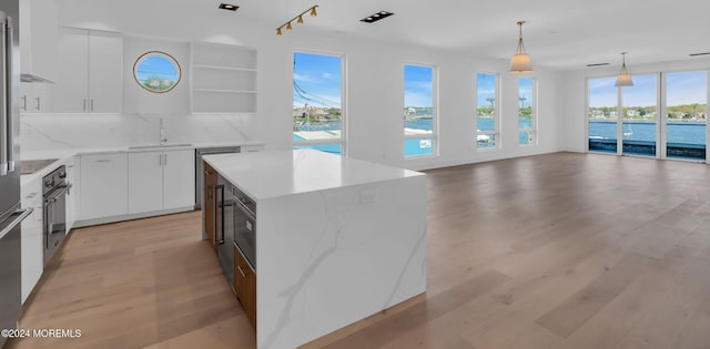 kitchen featuring decorative backsplash, sink, pendant lighting, white cabinets, and a kitchen island