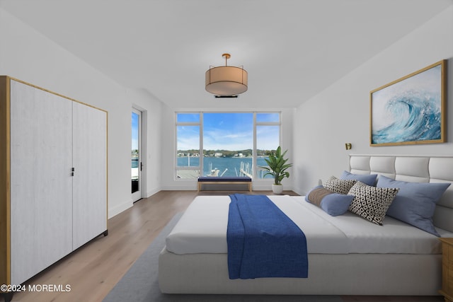 bedroom featuring light hardwood / wood-style floors and a water view