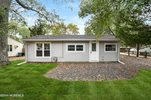 rear view of property with cooling unit and a yard