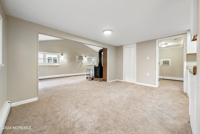 basement with light colored carpet, a wood stove, a baseboard heating unit, and a wall unit AC