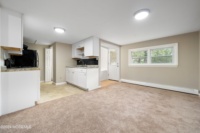 kitchen featuring white cabinetry, light carpet, a baseboard heating unit, and tasteful backsplash