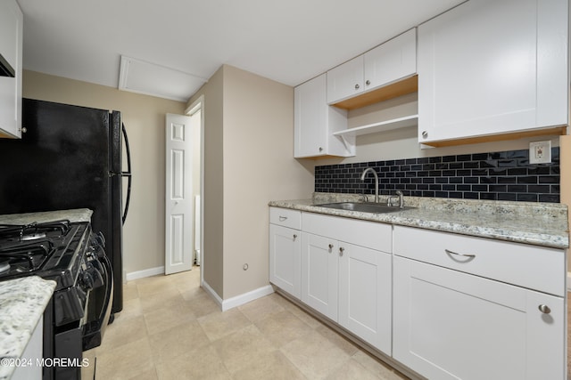 kitchen featuring light stone counters, sink, white cabinets, decorative backsplash, and black range with gas cooktop