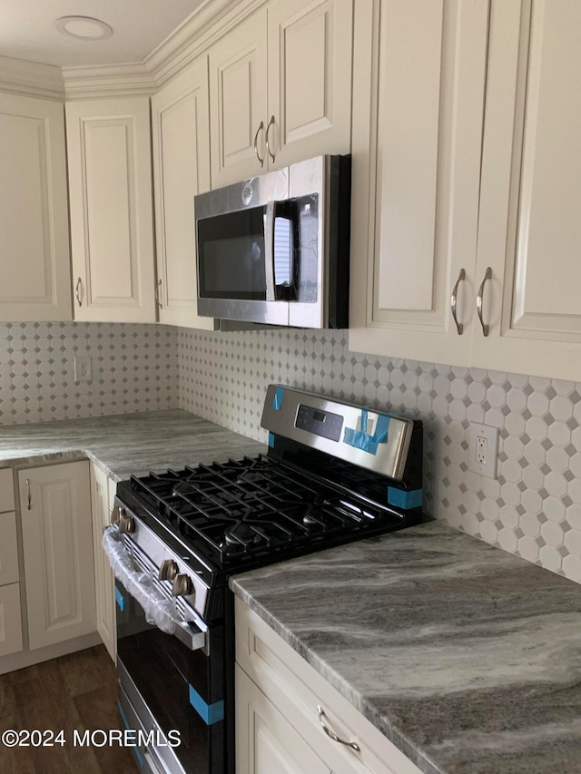 kitchen with appliances with stainless steel finishes, white cabinets, and tasteful backsplash