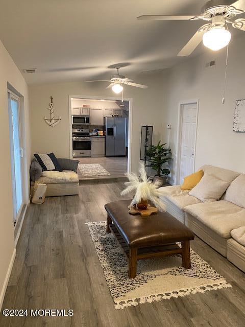 living room with ceiling fan, lofted ceiling, and dark hardwood / wood-style flooring