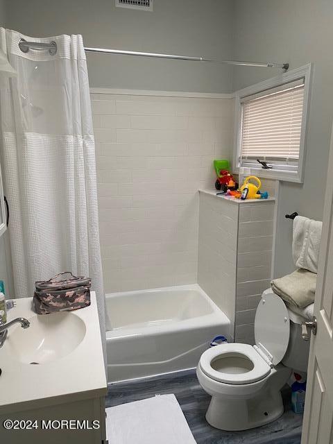 full bathroom featuring wood-type flooring, vanity, toilet, and shower / bath combination with curtain