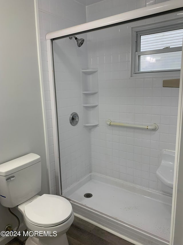 bathroom featuring walk in shower, hardwood / wood-style flooring, and toilet