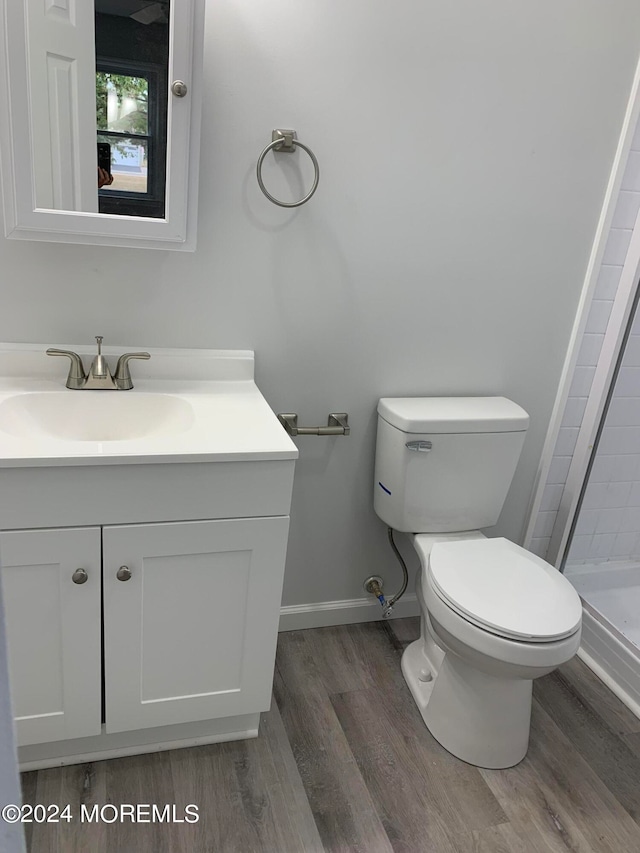 bathroom featuring walk in shower, wood-type flooring, vanity, and toilet