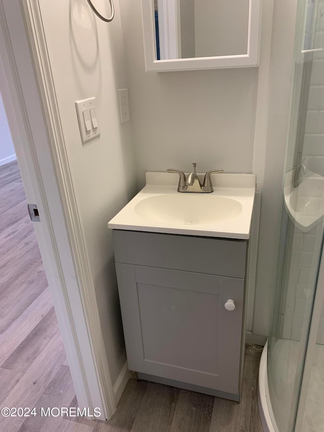 bathroom with wood-type flooring, vanity, and an enclosed shower