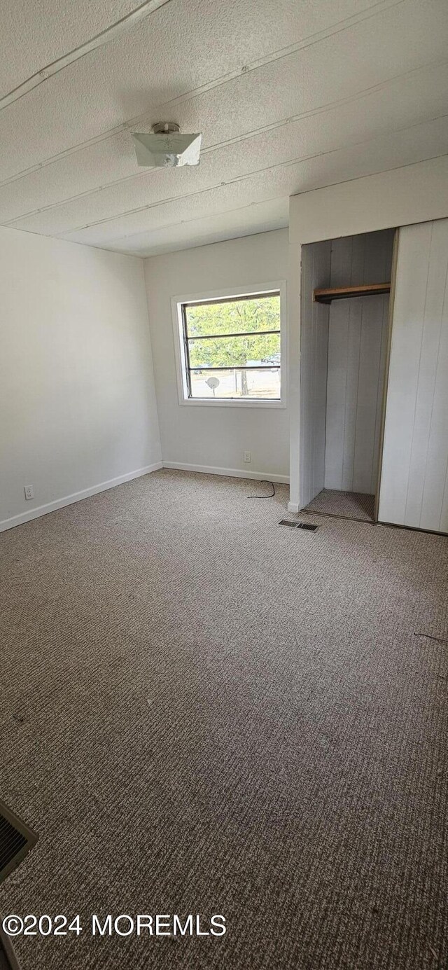 unfurnished bedroom with carpet, a closet, and a textured ceiling