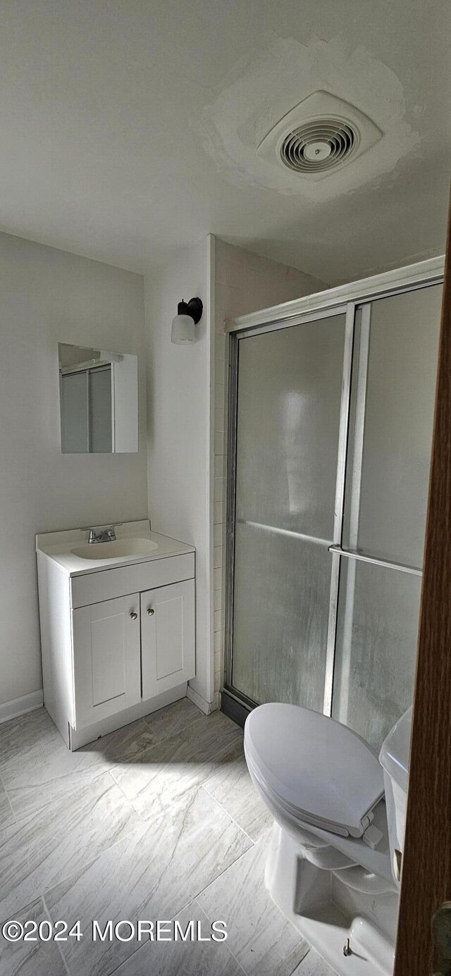 bathroom featuring vanity, hardwood / wood-style flooring, a shower with shower door, and toilet