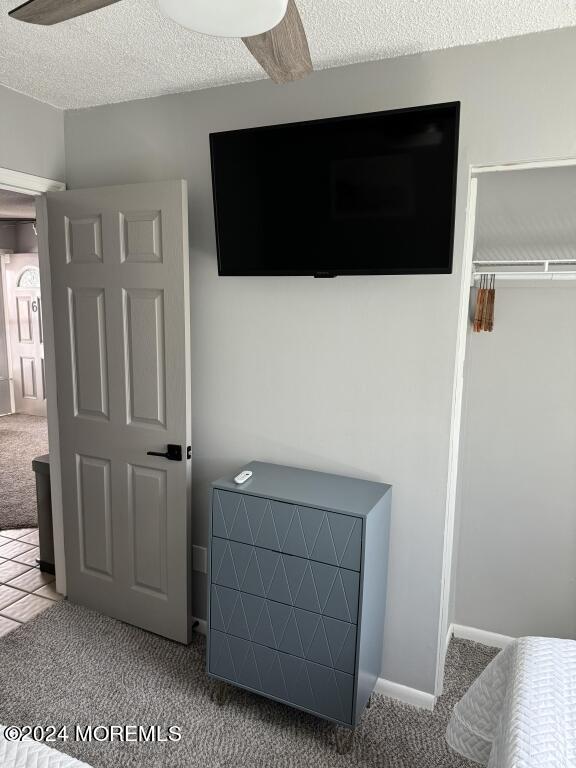 carpeted bedroom featuring ceiling fan, a textured ceiling, and a closet