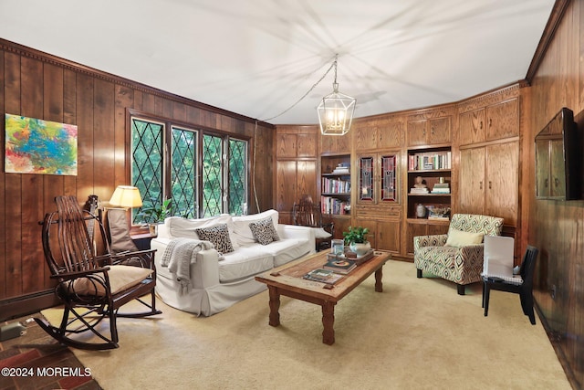 living area with wood walls, ornamental molding, light colored carpet, and an inviting chandelier