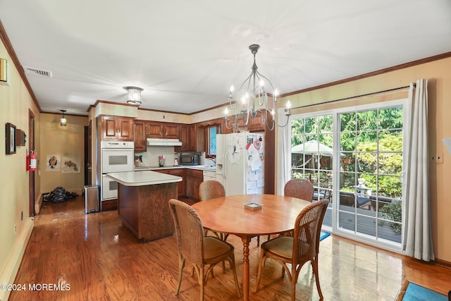 dining area with a chandelier, dark wood-type flooring, crown molding, and sink