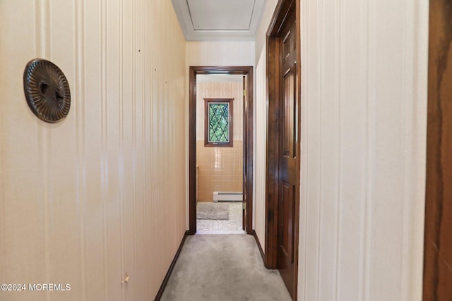 hallway with wooden walls, light colored carpet, and a baseboard heating unit